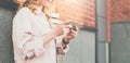 Close-up of smartphone in hands of young woman standing outdoors against wall background. Royalty Free Stock Photo