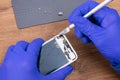 Close-up of a smartphone screen repair, on a wooden background, fragments are removed from the case with a scalpel