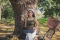 Close up smiled Asian woman in casual wear sitting and working with laptop under the tree next to a white bicycle in a public park Royalty Free Stock Photo