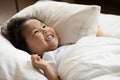 Smiling adorable little asian ethnic kid waking up in morning.