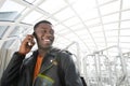 Close up smiling african american man with leather jacket talking on cellphone at station Royalty Free Stock Photo