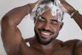 Close up smiling African American man washing hair with shampoo Royalty Free Stock Photo