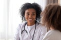 Close up smiling African American pediatrician doctor listening to patient Royalty Free Stock Photo