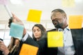 Close-up of smiling African businessman brainstorm meeting with colleagues by using colorful sticky paper note on glass wall. Royalty Free Stock Photo