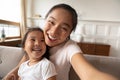 Close up smiling Asian mother and little girl taking selfie