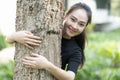Smiling asian young woman hugging tree at the park Royalty Free Stock Photo