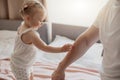 Close up of smiling baby girl touch daddy& x27;s hand standing on bed Royalty Free Stock Photo