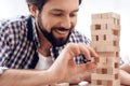 Close up. Smiling bearded man removes wooden blocks from tower. Royalty Free Stock Photo