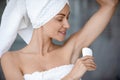 Close up beautiful woman wearing towel applying antiperspirant after shower Royalty Free Stock Photo