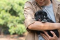 Close up Smiling black puppy dog in embracing owner, people love the animal friend of the family. comfort zone at garden home