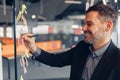 Close up of smiling businessman is writing on sticky notes on motivation board in modern office Royalty Free Stock Photo