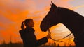 CLOSE UP: Smiling Caucasian woman looking at her beautiful horse at sunset. Royalty Free Stock Photo