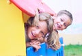 Close up of smiling childs face hiding behind wooden element of slide at playground on summer day. Royalty Free Stock Photo