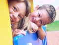 Close up of smiling childs face hiding behind wooden element of slide at playground on summer day. Royalty Free Stock Photo