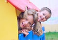 Close up of smiling childs face hiding behind wooden element of slide at playground on summer day. Royalty Free Stock Photo