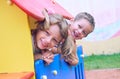 Close up of smiling childs face hiding behind wooden element of slide at playground on summer day. Royalty Free Stock Photo