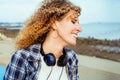 Close up smiling curly hair caucasian woman with large headphones walking outdoor. Enjoy the moment and music. Freedom Royalty Free Stock Photo