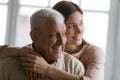 Close up smiling dreamy elderly man and young woman hugging Royalty Free Stock Photo