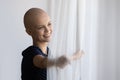 Close up smiling dreamy hairless woman opening curtains in morning Royalty Free Stock Photo