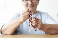 Close-up of smiling elderly person holding rosary with cross