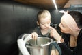 Close up smiling gentle woman in headband touching little boy nose to wake up near steel blender in kitchen. Little chef