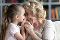 Close up smiling grandmother and little granddaughter talking, sharing secrets Royalty Free Stock Photo