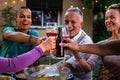 Close-up of smiling, happy friends having fun, toasting with wine and beer during garden dinner party at night. Royalty Free Stock Photo