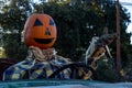 Smiling, happy, welcoming, fun friendly pumpkin head scarecrow driving an old truck to a halloween harvest party