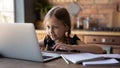 Close up smiling little girl using laptop, studying online at home Royalty Free Stock Photo