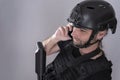 Close up of a smiling man communicating over the phone in his airsoft equipment showing helmet, vest and an automated