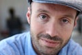 Close up of a smiling man in newsboy hat looking to camera