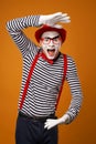 Close up smiling mime man in red hat, white gloves and striped t-shirt on blank orange background Royalty Free Stock Photo