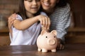 Close up mother and daughter putting coin into piggy bank Royalty Free Stock Photo