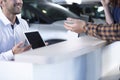 Close-up of smiling professional car seller with tablet offering Royalty Free Stock Photo