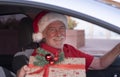 Close-up smiling senior bearded man inside his car wearing a Santa hat ready to home delivery of Christmas gifts Royalty Free Stock Photo