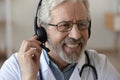 Close up smiling senior doctor wearing headset working online Royalty Free Stock Photo