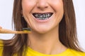 Close up of smiling woman brushing teeth with eco friendly bamboo toothbrush with black charcoal whitening toothpaste