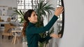 Close up smiling woman hanging or fixing mirror, decorating apartment