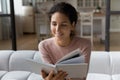 Close up smiling woman reading book, sitting on cozy couch Royalty Free Stock Photo