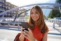 Close up of smiling woman wearing orange blouse texting on mobile phone in sustainable city