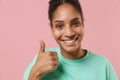 Close up of smiling young african american woman girl in green sweatshirt posing isolated on pastel pink background Royalty Free Stock Photo