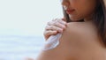 Close up Smiling young asian woman applying a sunscreen lotion on shoulder her skin on a seaside beach tropical resting and relaxa Royalty Free Stock Photo