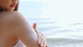 Close up Smiling young asian woman applying a sunscreen lotion on shoulder her skin on a seaside beach tropical resting and relaxa Royalty Free Stock Photo