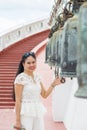 Close up smiling young Asian woman in a white shirt standing and touching a bell in Buddish temple Royalty Free Stock Photo