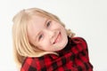 Close up of a smiling young blonde preteen girl with head tilted on a white studio background