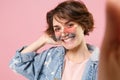 Close up of smiling young brunette woman girl in casual denim jacket glasses posing isolated on pastel pink background Royalty Free Stock Photo