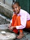 Close up of smiling young Buddhist novice nun sitting on step, Myanmar