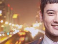 Close-up of smiling young businessman, city lights background