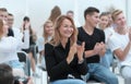 close up. smiling young woman applauding sitting in conference r Royalty Free Stock Photo