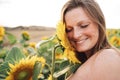 Close up of smiling young woman with eyes closed touching sunflower on face at field Royalty Free Stock Photo